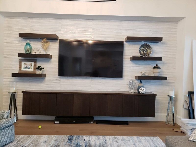 A living room with a flat screen tv and shelves.