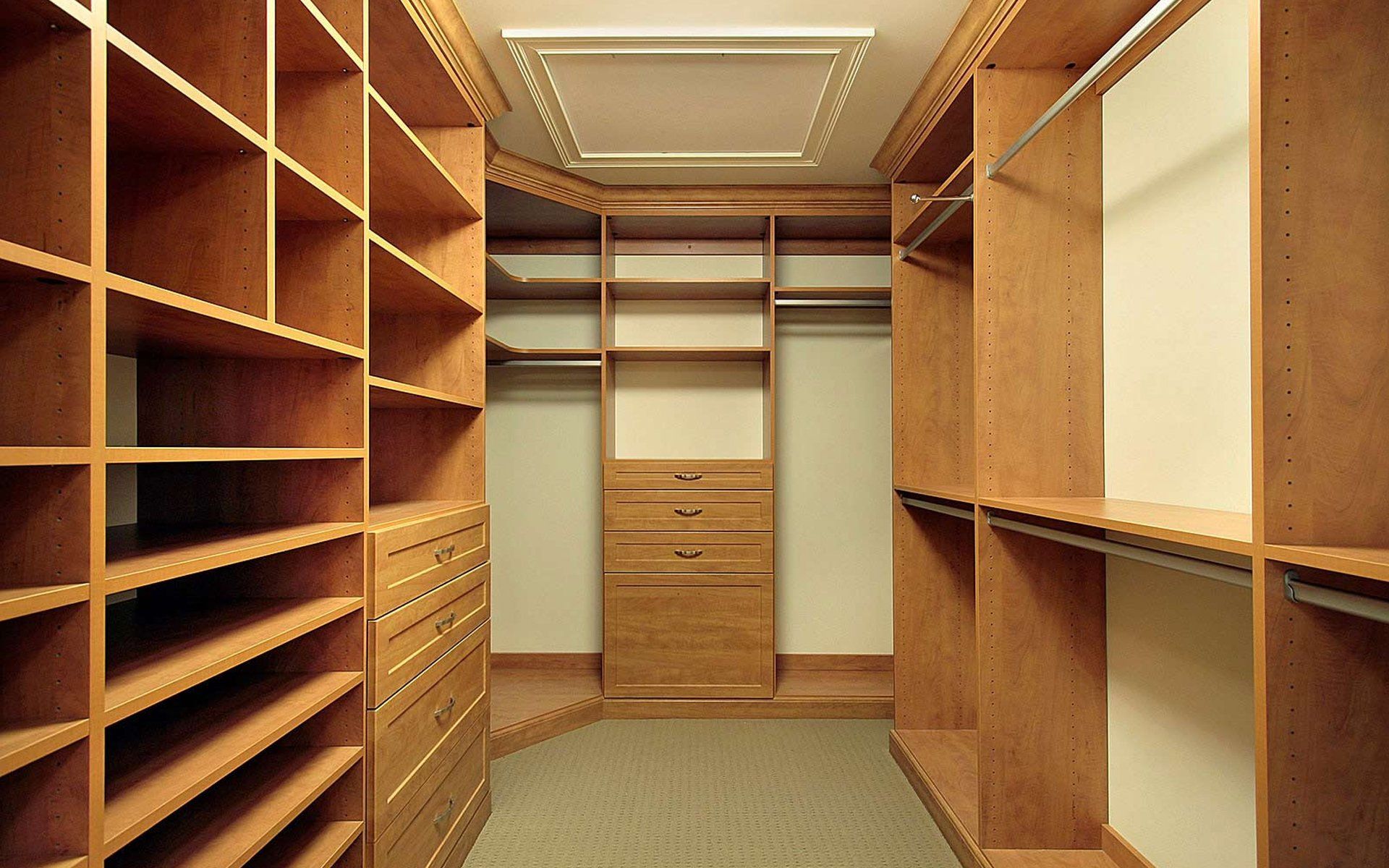 An empty walk in closet with wooden shelves and drawers