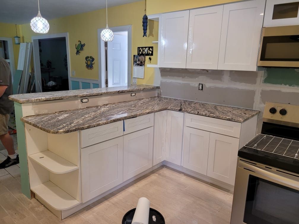 Kitchen with white cabinets, granite countertops, and stainless steel appliances; a renovation in progress.