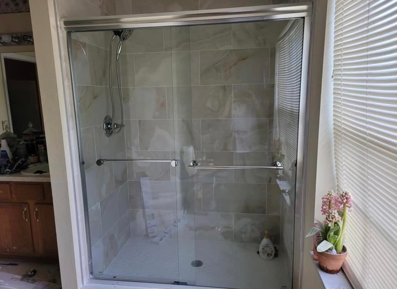 Shower stall with sliding glass doors and tiled walls.