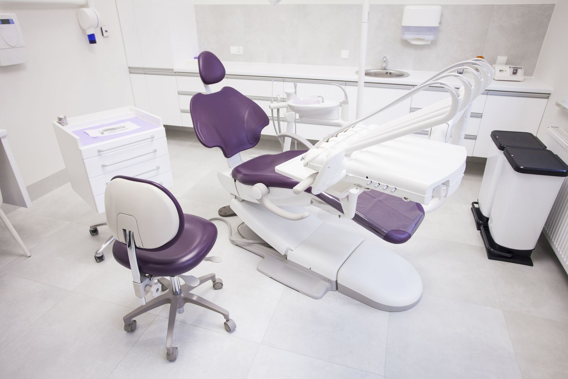 Dental office with purple and white equipment, including a chair and a stool.