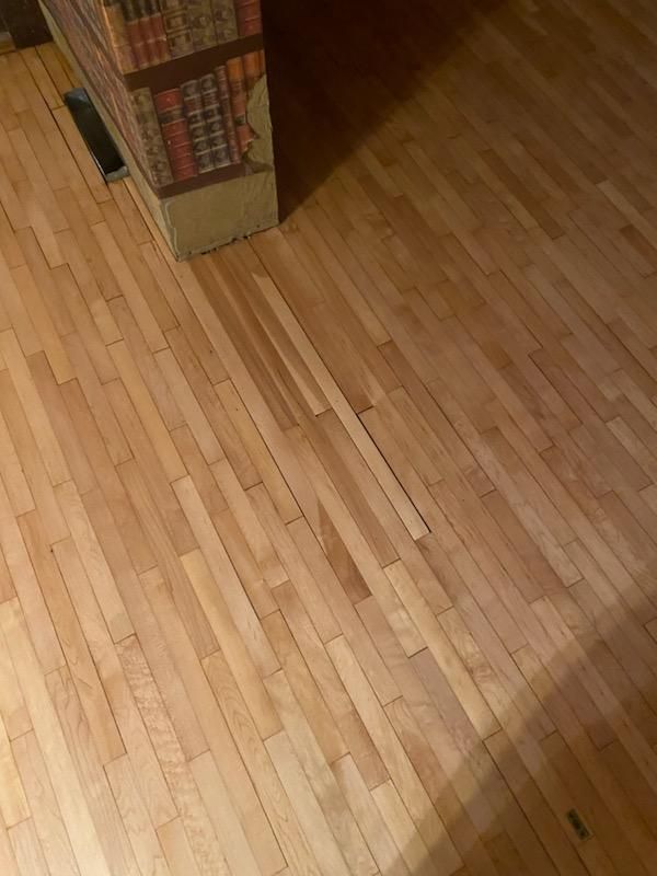 A close up of a wooden floor with a bookshelf in the background.