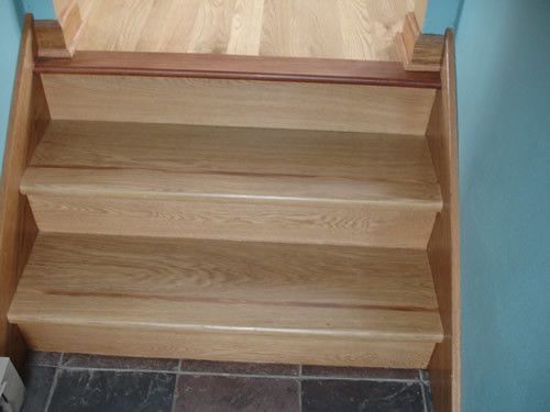 A set of wooden stairs leading up to a tiled floor.