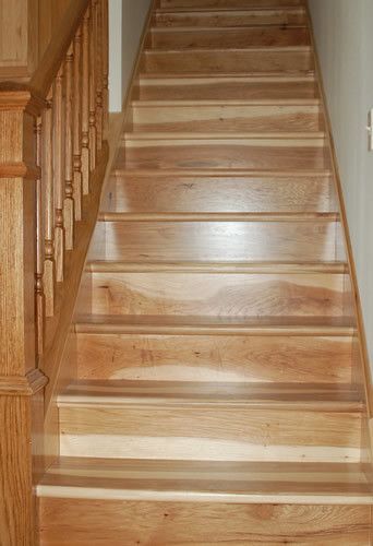 A wooden staircase with a wooden railing leading up to the second floor of a house.