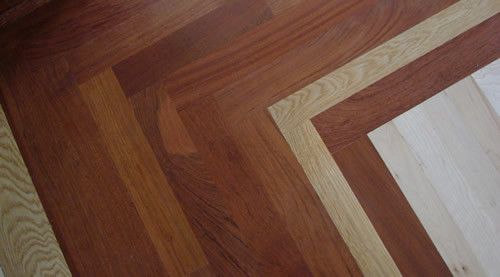 A close up of a wooden floor with a herringbone pattern.