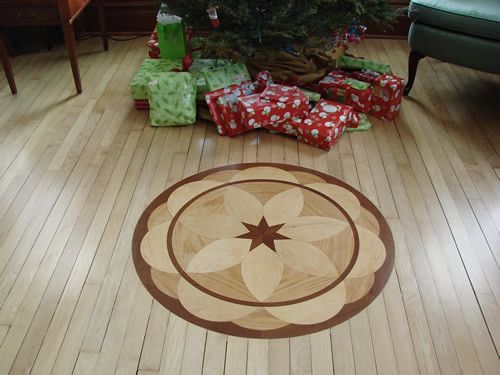 A wooden floor with a flower design and a christmas tree in the background
