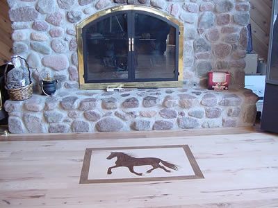 A stone fireplace with a horse stenciled on the floor