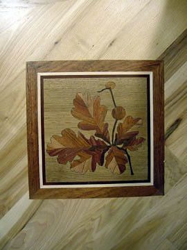 A picture of leaves in a wooden frame on a wooden floor.