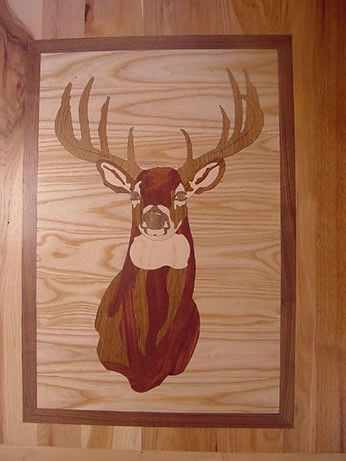 A wooden painting of a deer 's head in a wooden frame.