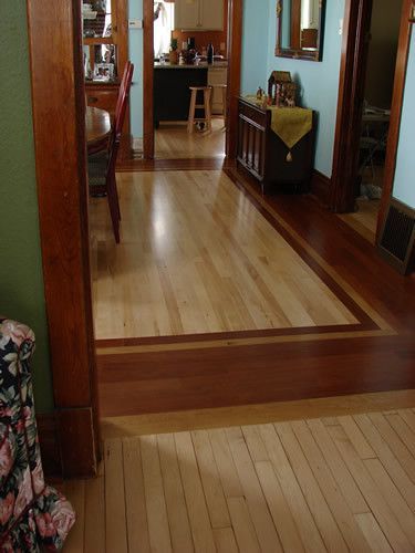 A hallway with hardwood floors leading to a kitchen