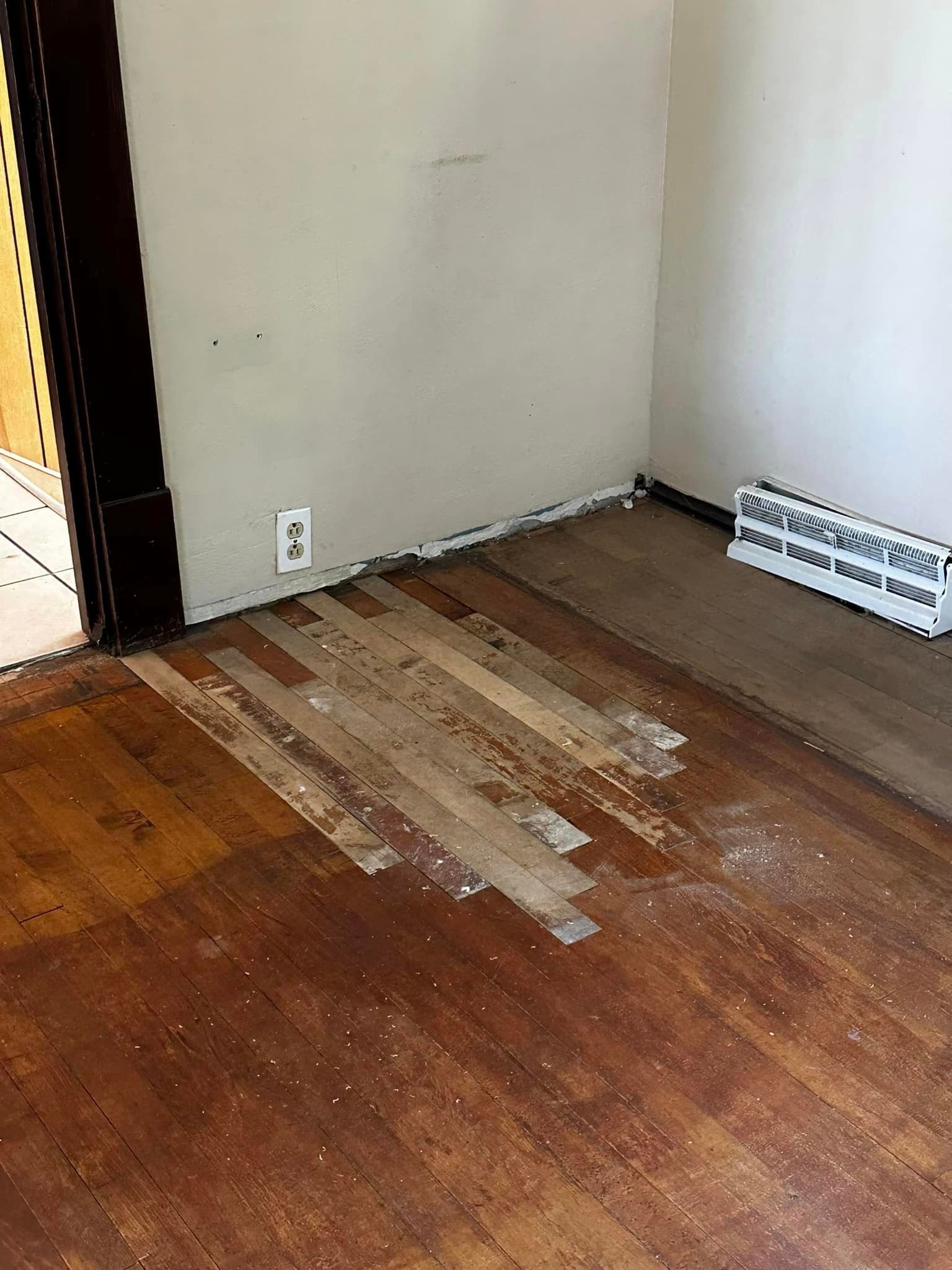 A room with a wooden floor and a white wall.