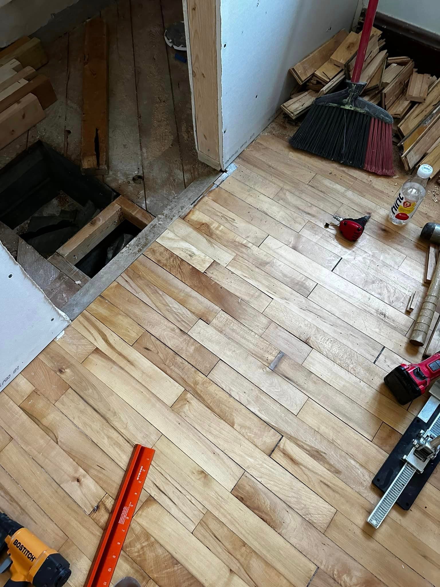A wooden floor with tools and a broom on it.