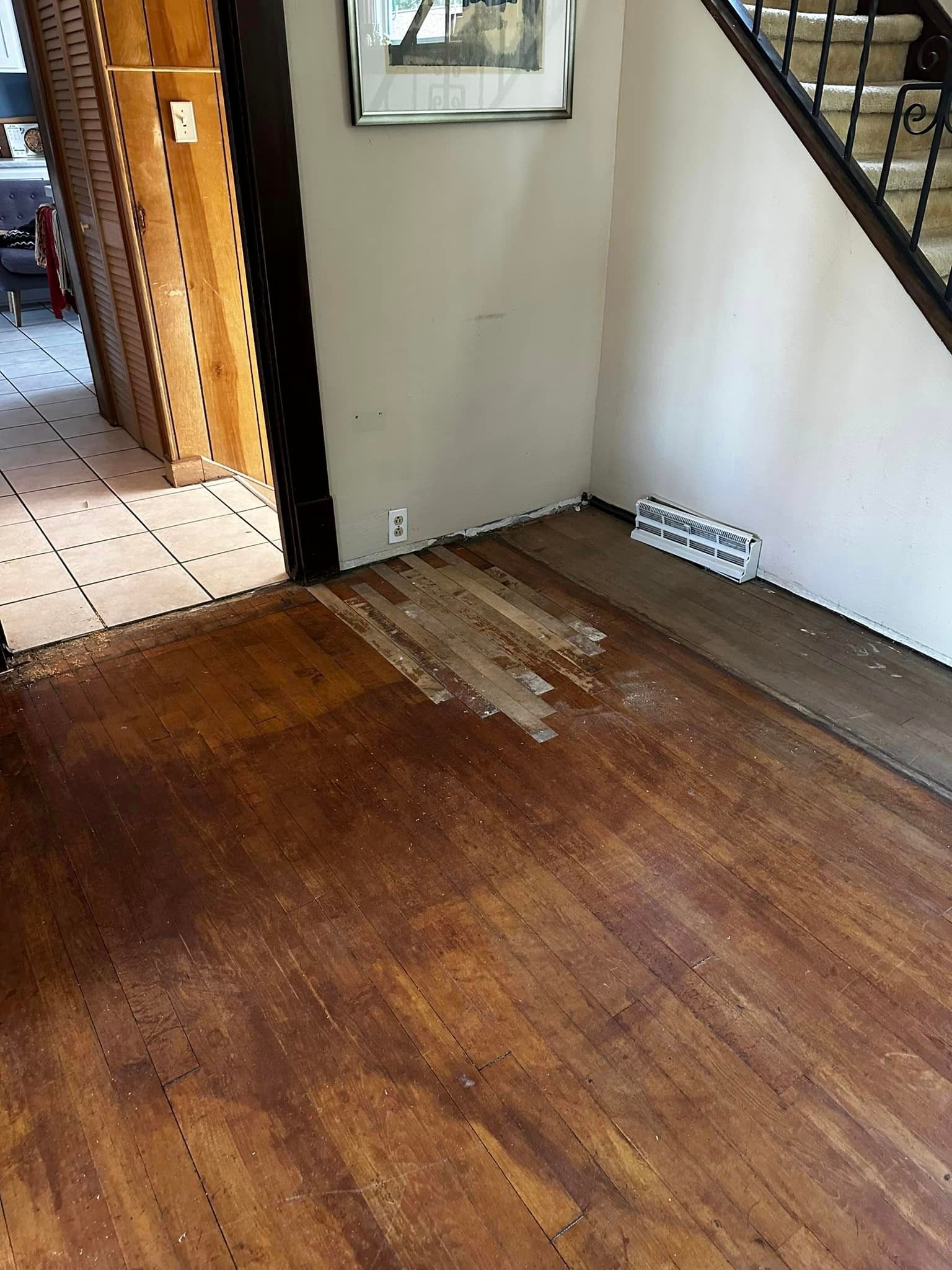 A wooden floor in a room next to a staircase.