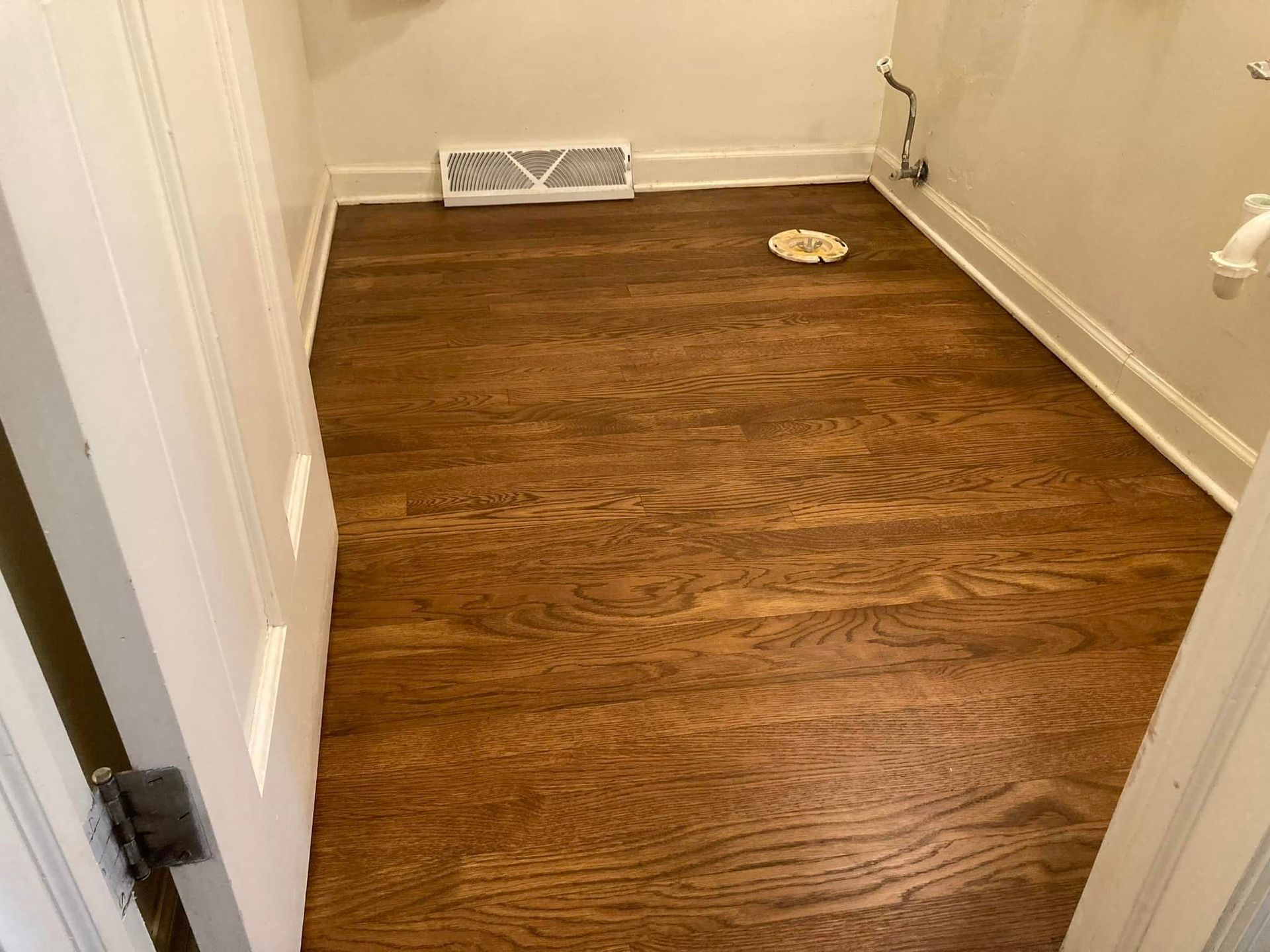 A laundry room with hardwood floors and a toilet.