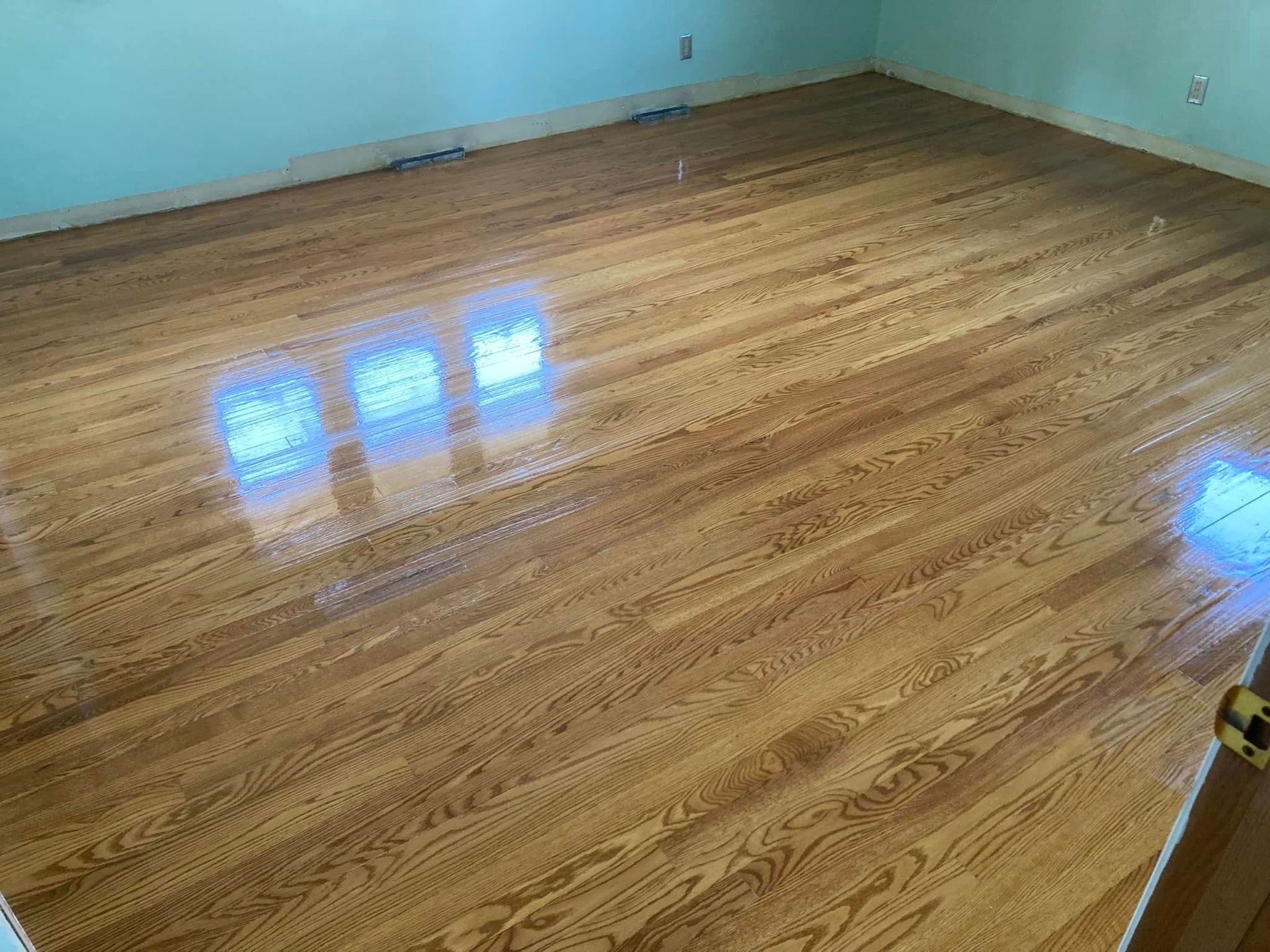 A room with a wooden floor and three windows.