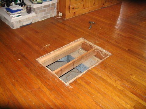 A wooden floor with a hole in it in a living room.