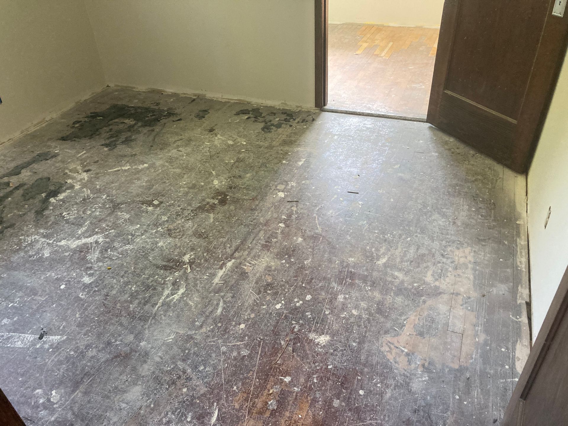 A room with a dirty floor and a door.