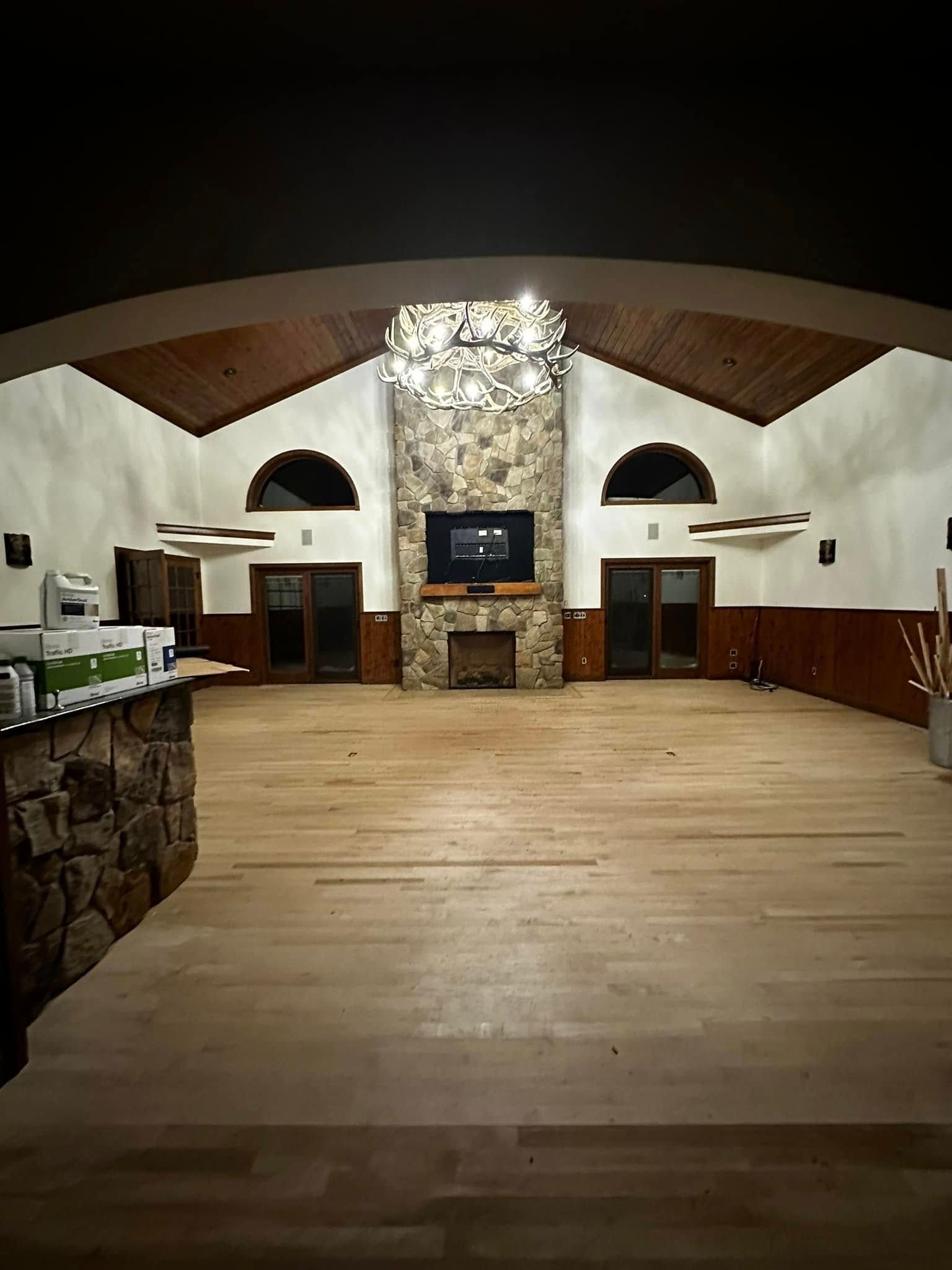 A large room with a wooden floor and a fireplace.