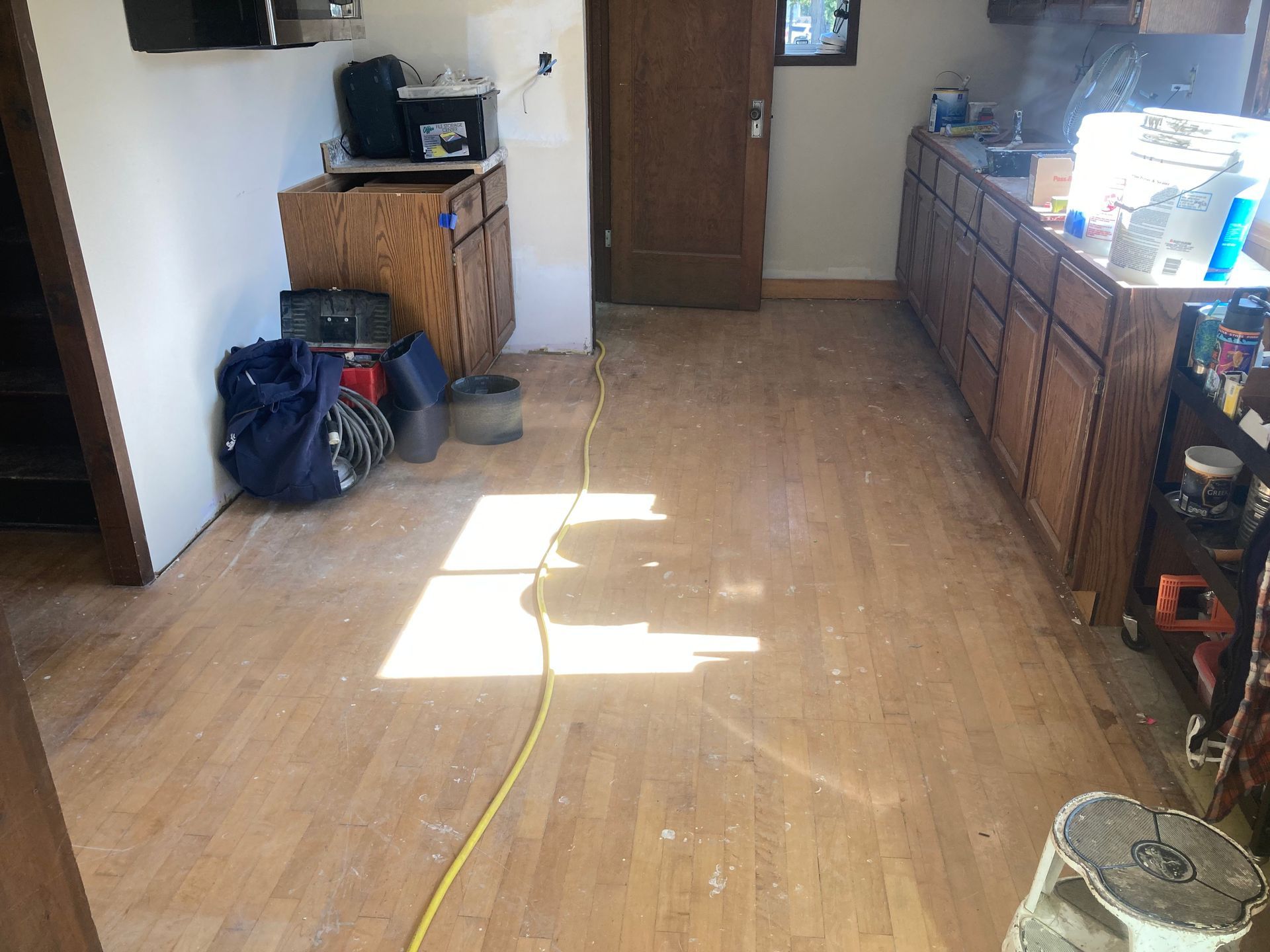 A kitchen with hardwood floors and a yellow cord.