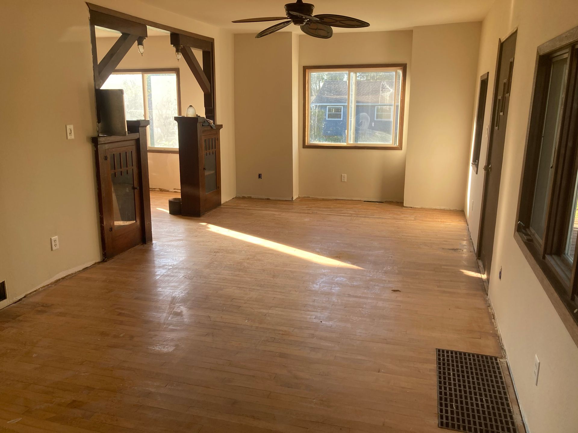 An empty living room with hardwood floors and a ceiling fan.