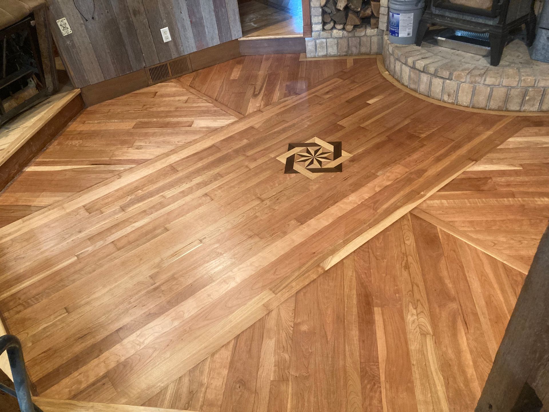 A wooden floor in a living room with a fireplace.
