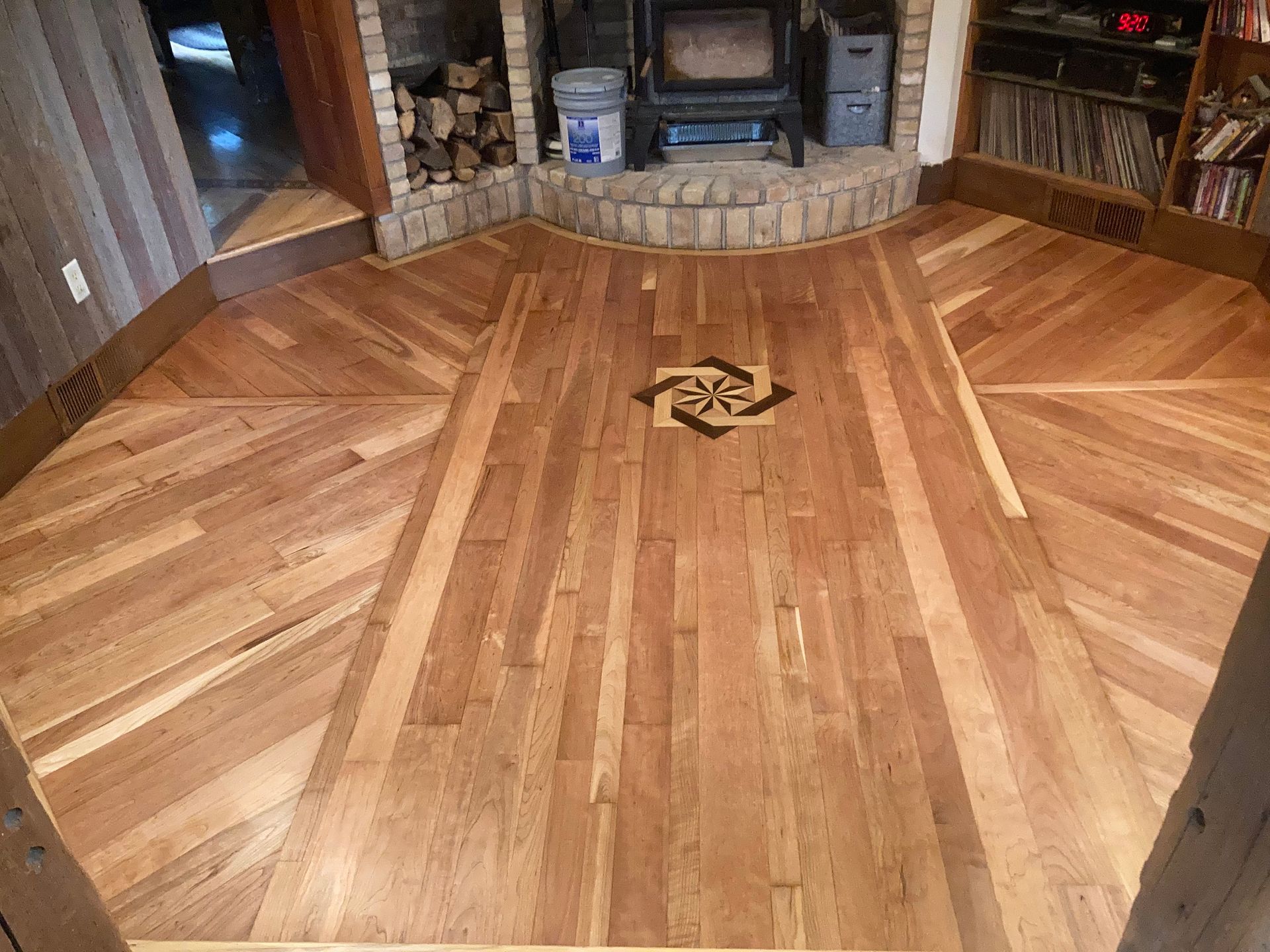 A wooden floor in a living room with a fireplace in the background.