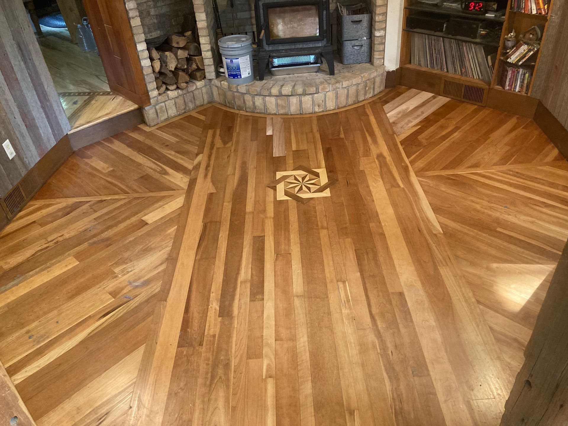 A wooden floor in a living room with a fireplace.