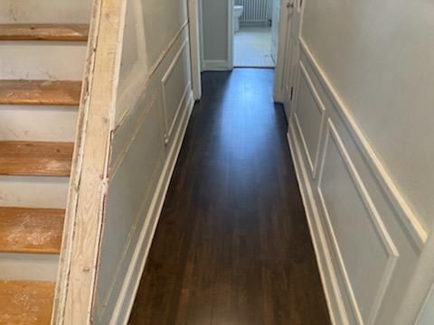 A hallway with wooden floors and stairs in a house