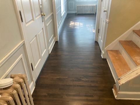 A hallway with hardwood floors and stairs in a house