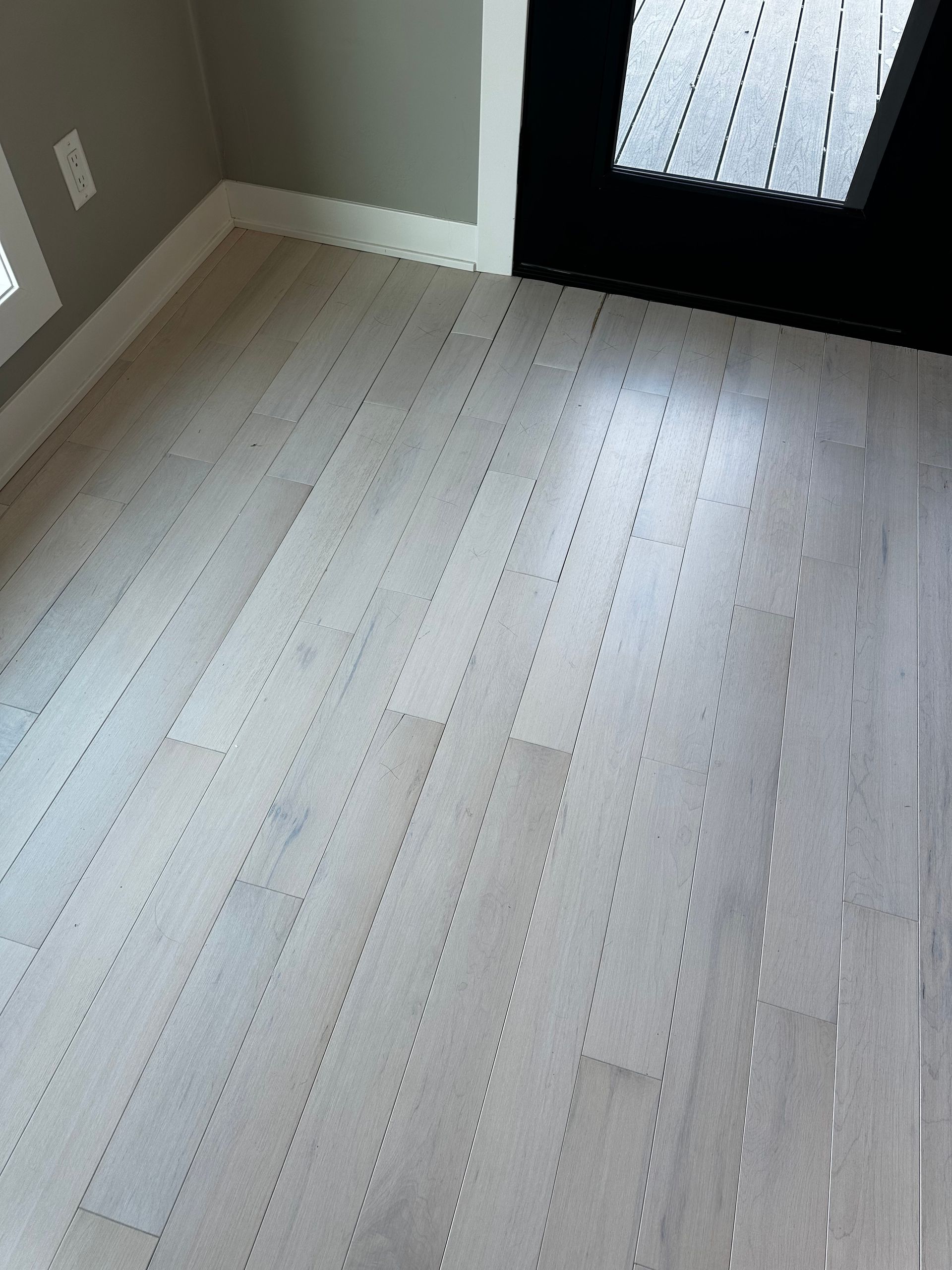 A white wooden floor in a room next to a door.