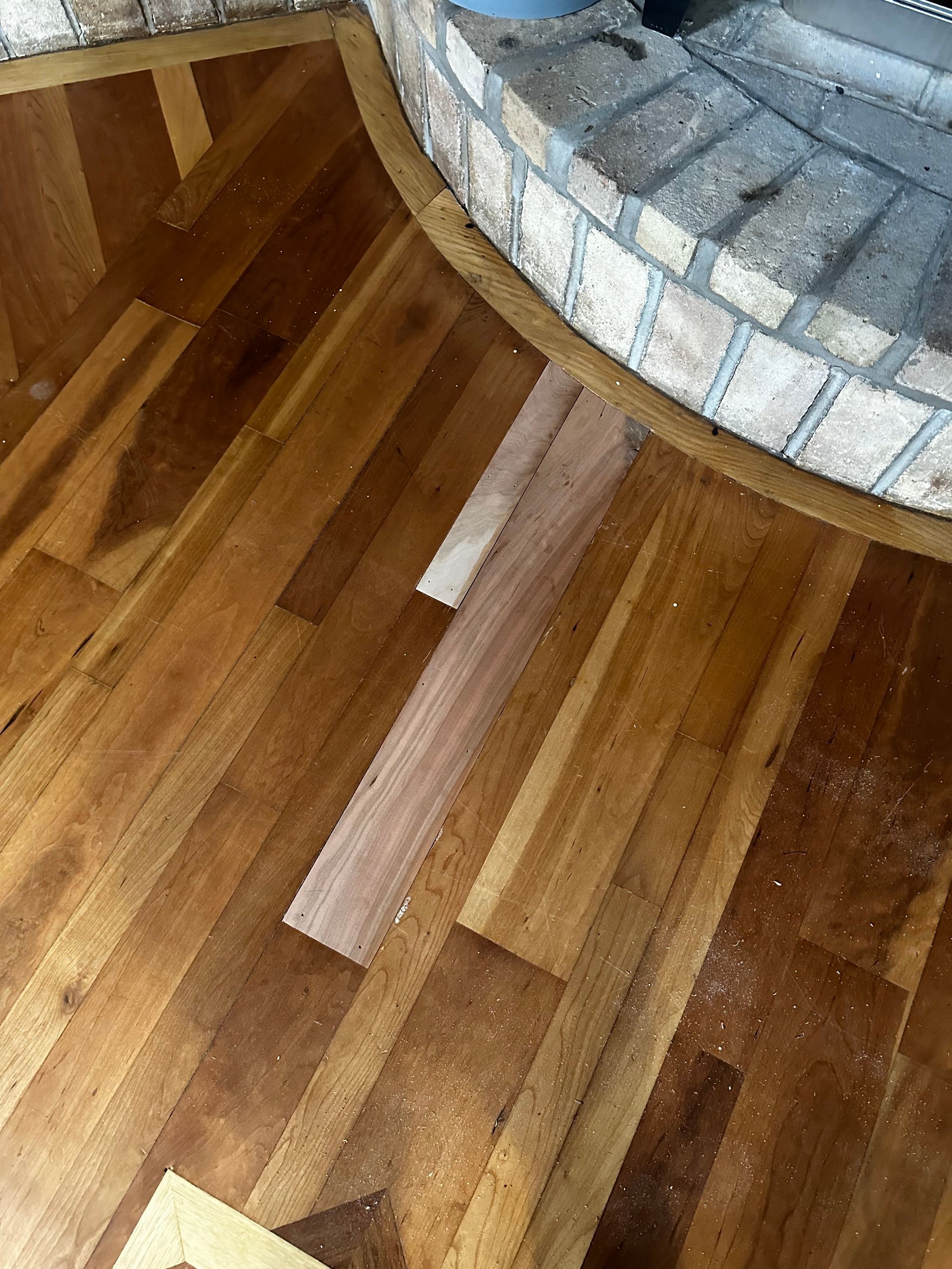 A wooden floor with a brick fireplace in the background.