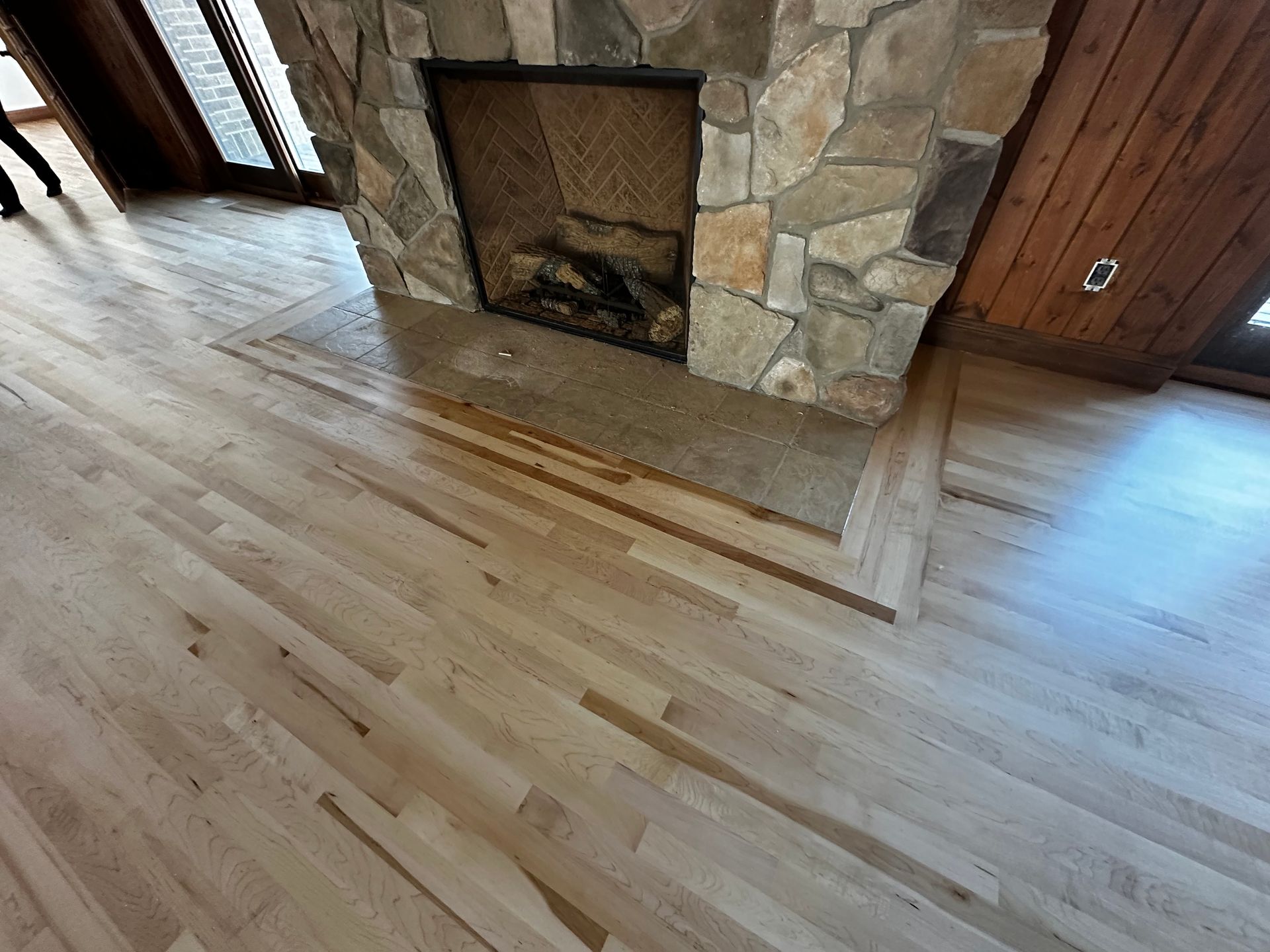 A stone fireplace with a wooden floor in front of it