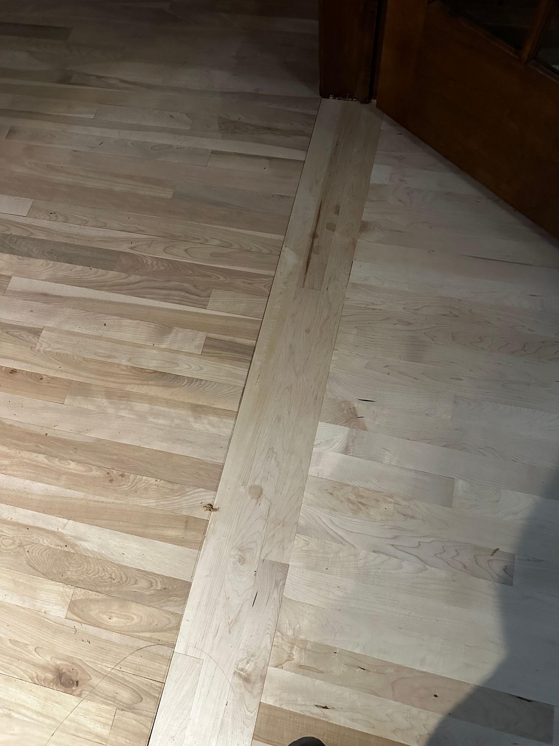 A close up of a wooden floor with a door in the background.