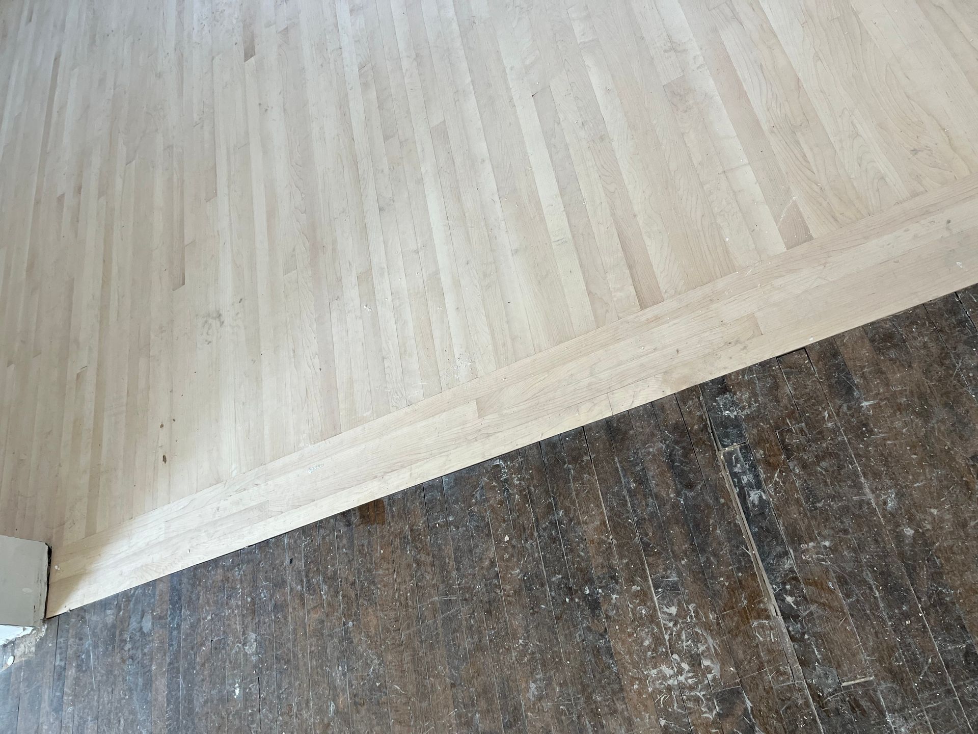 A close up of a wooden floor next to a concrete floor.