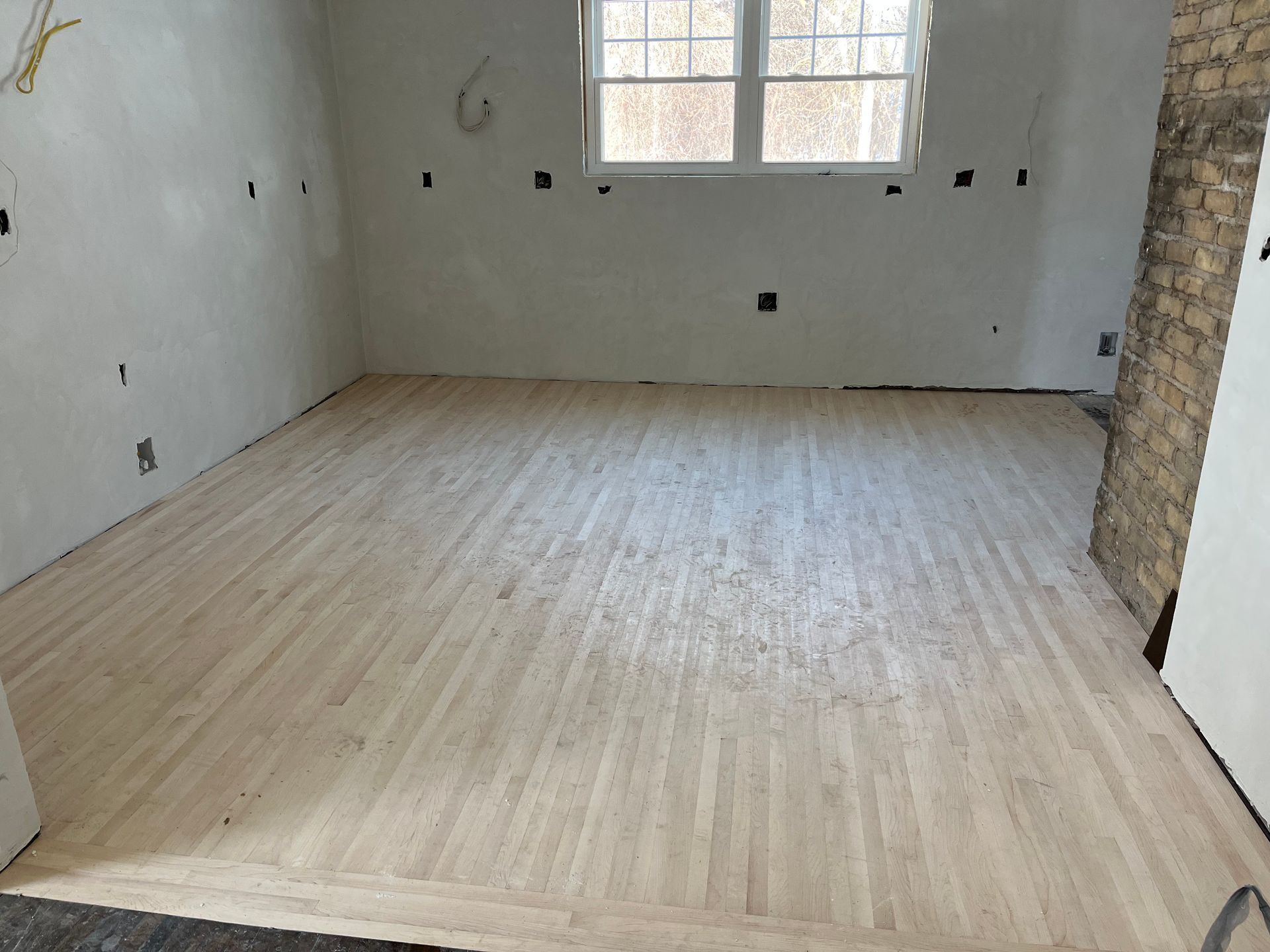 A room with a wooden floor and a window.