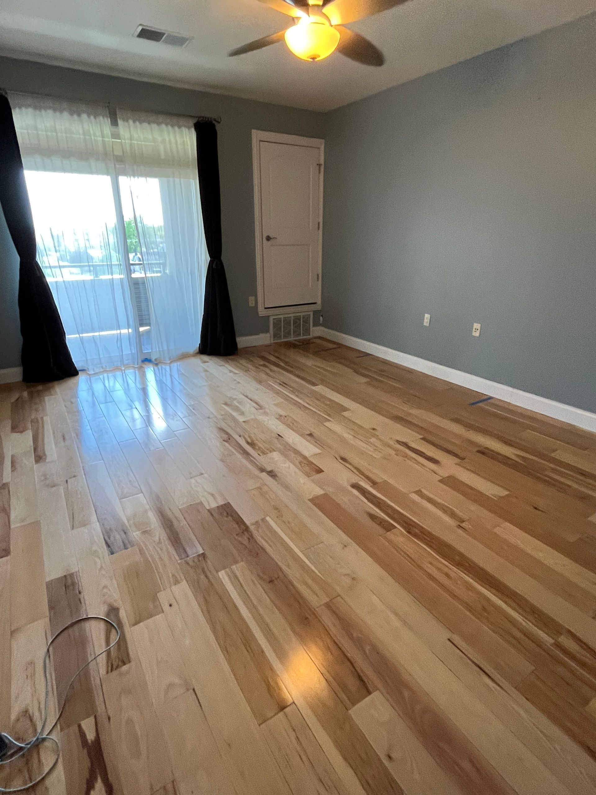 A living room with hardwood floors and a ceiling fan.