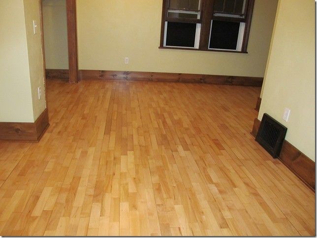 An empty room with hardwood floors and two windows