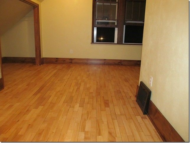An empty room with hardwood floors and two windows