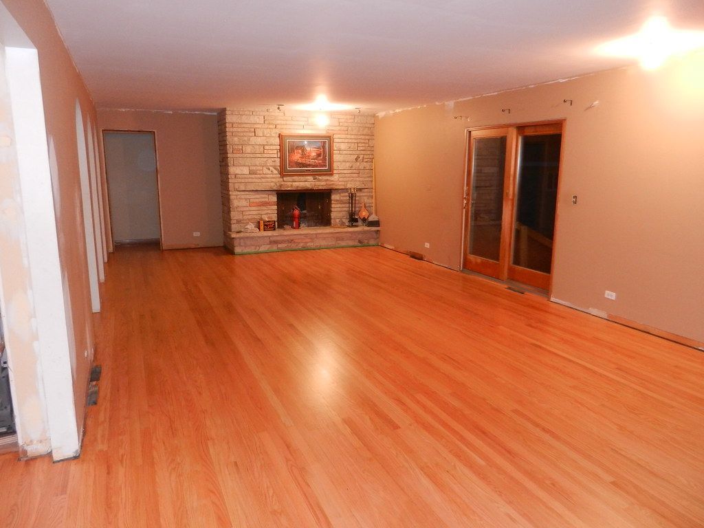 An empty living room with hardwood floors and a fireplace