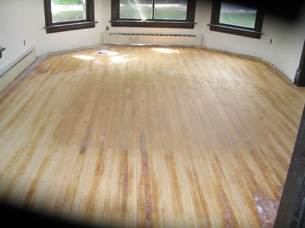 An empty room with a wooden floor and windows