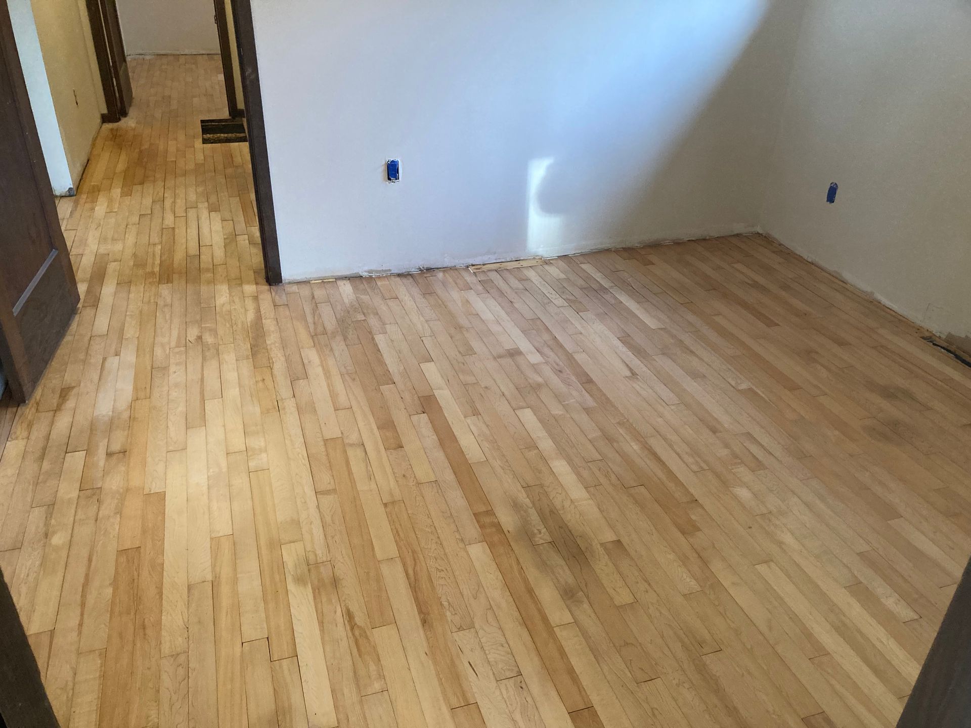 A room with a wooden floor and a white wall.