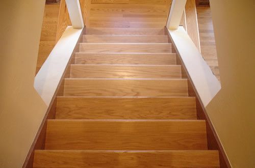 A wooden staircase with a white railing and a wooden floor