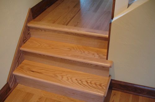 A close up of a wooden staircase with hardwood floors.