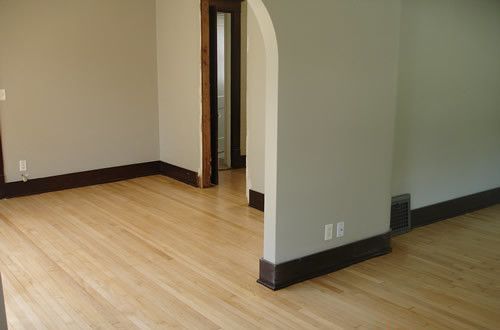 An empty room with hardwood floors and a doorway.