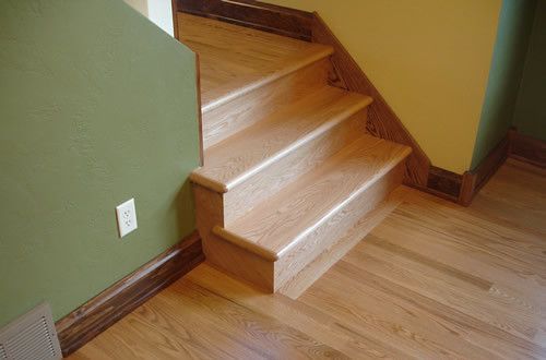 A wooden staircase with a wooden floor and a green wall.
