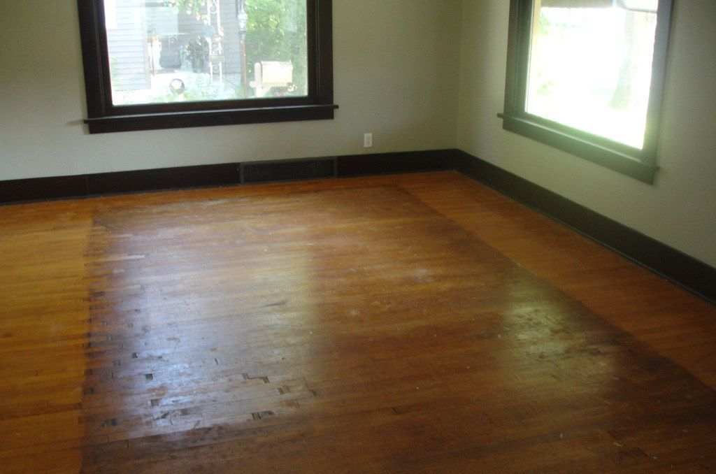 An empty living room with hardwood floors and a window.