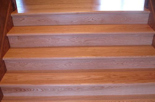 A close up of a wooden staircase with a wooden railing.