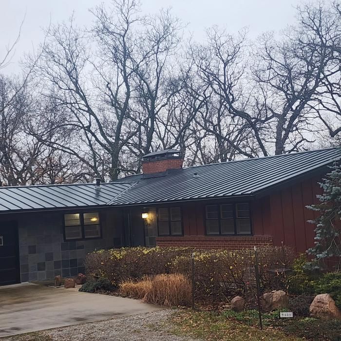 A red house with a metal roof and trees in the background.