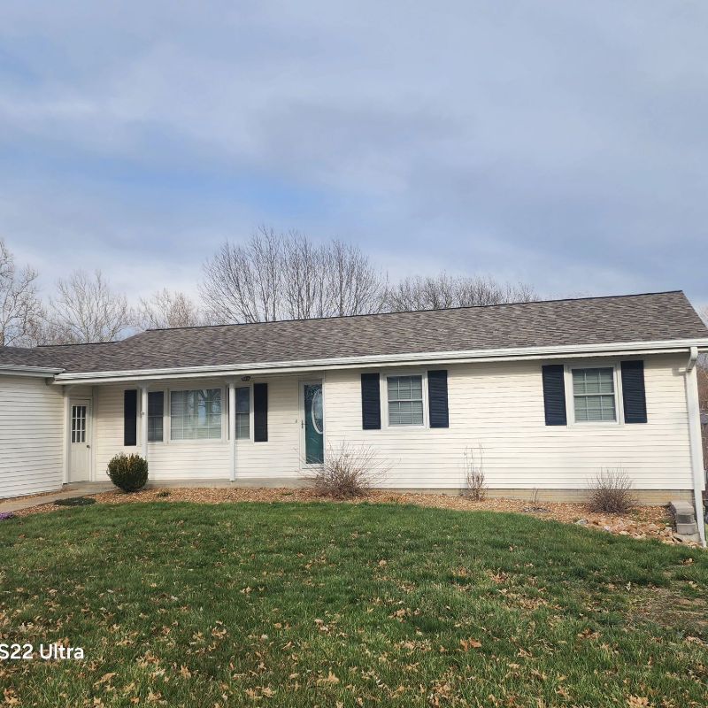 A white house with black shutters and a gray roof