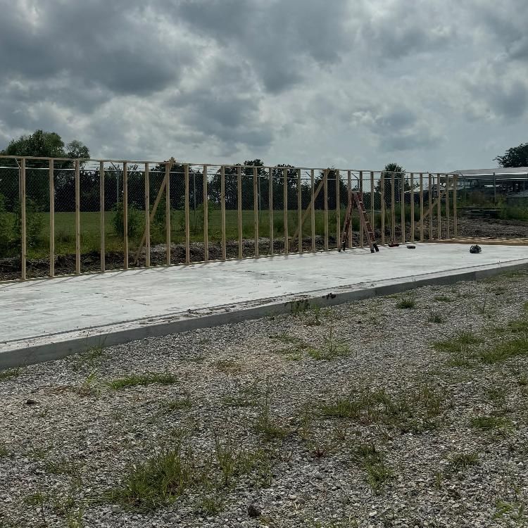 A large wooden structure is being built on a gravel road